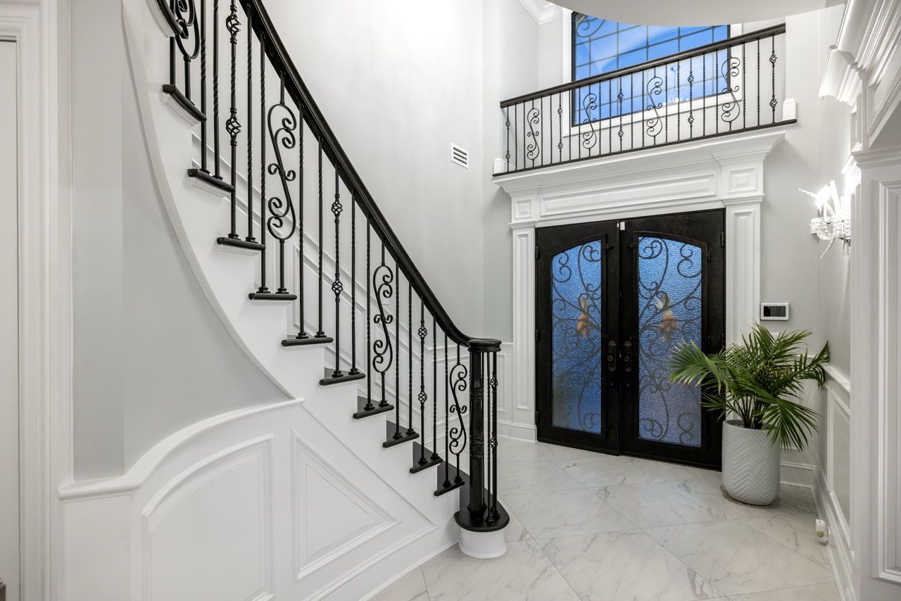 Two-story foyer with a curved staircase and glass front doors
