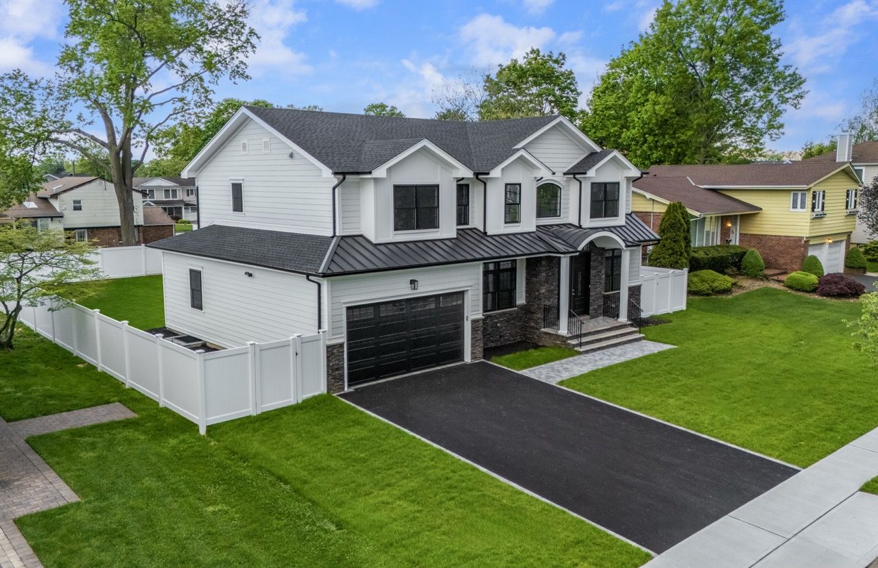 Drone view of a new white home, driveway and lawn