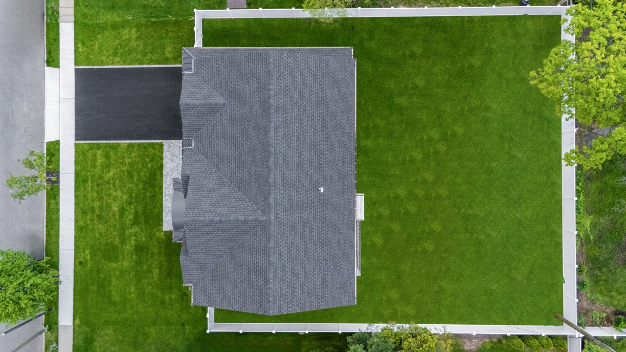 Overhead drone shot of a roof and fenced backyard