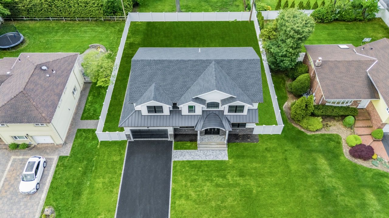 Drone view of a home with its driveway and backyard