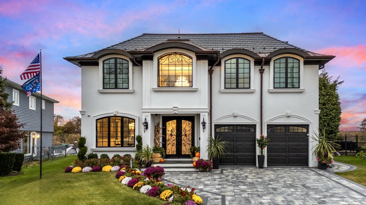 Front of a stucco home at dusk under a pink sky